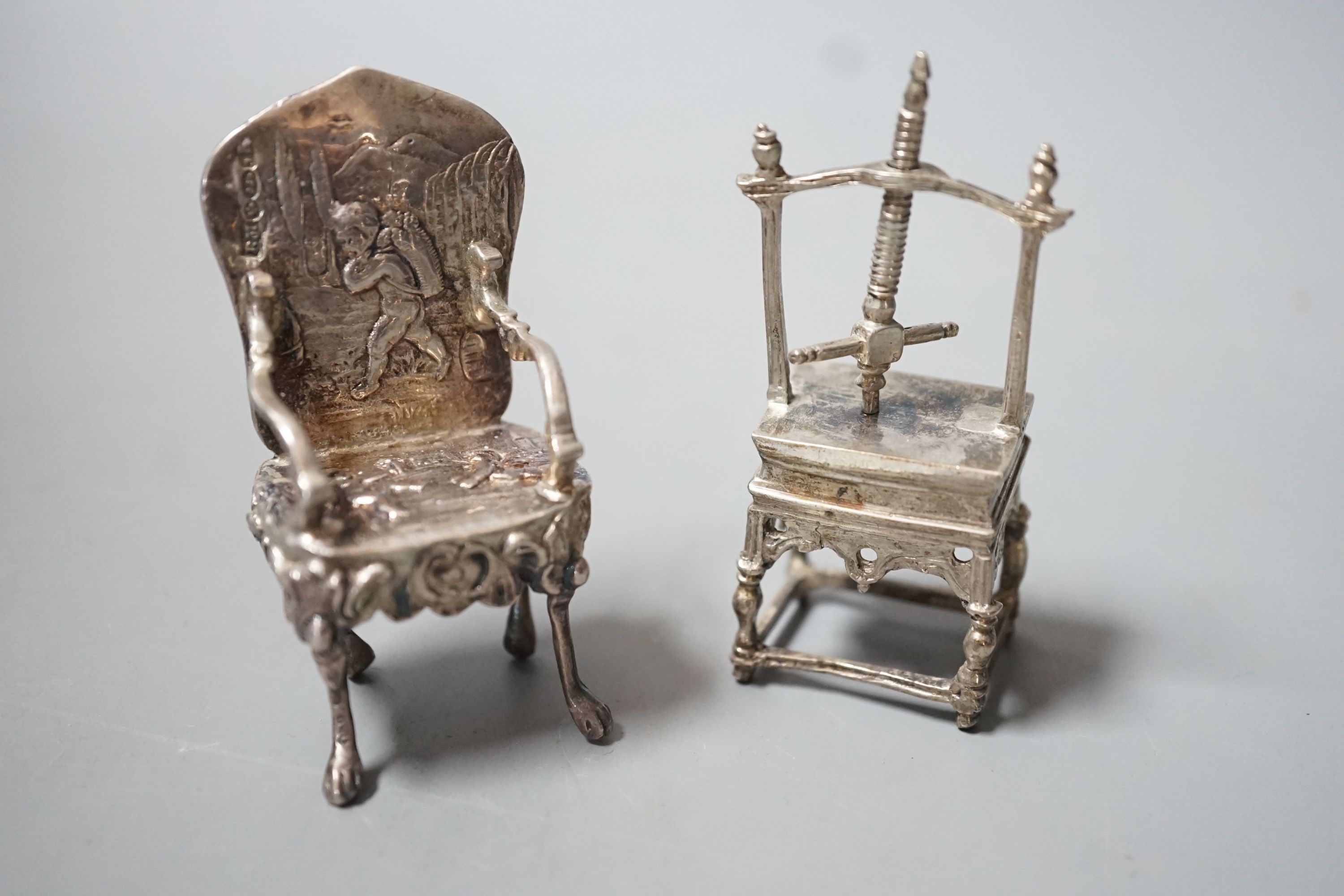An Edwardian silver miniature model of an armchair, import marks for Glasgow, 1902, 64mm and a white metal model of a press.